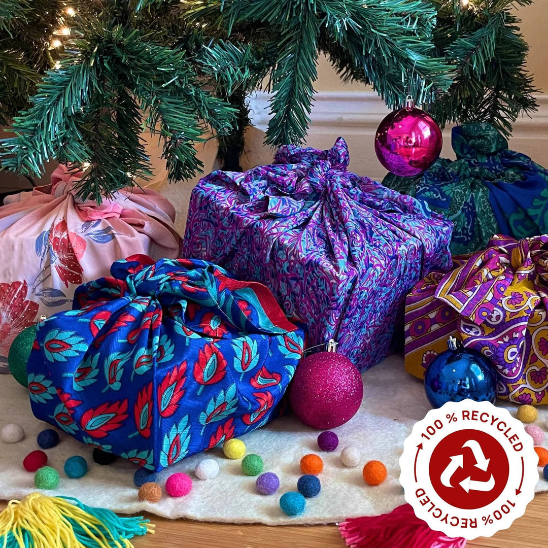 five presents under a christmas tree wrapped in various colors sari silk furoshiki wrapping.