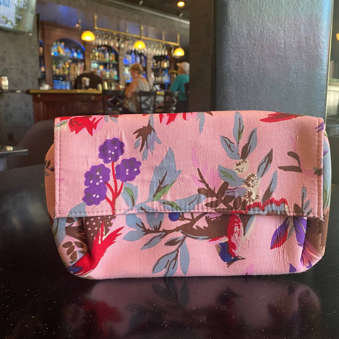 Pink cotton clutch sitting on a table with the bar in the background.