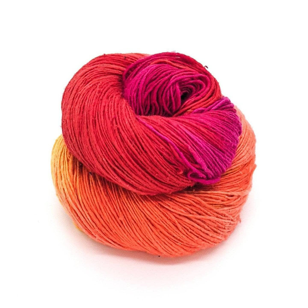 Lace weight silk yarn in color way color surge (orange, yellow and pink) in front of white background.