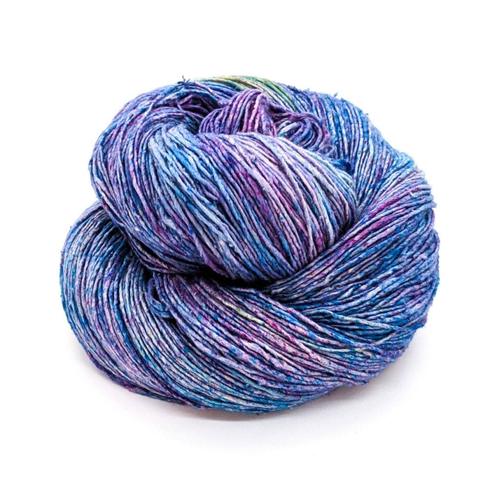 single skein of tonal blue and purple lace weight silk yarn in front of a white background.