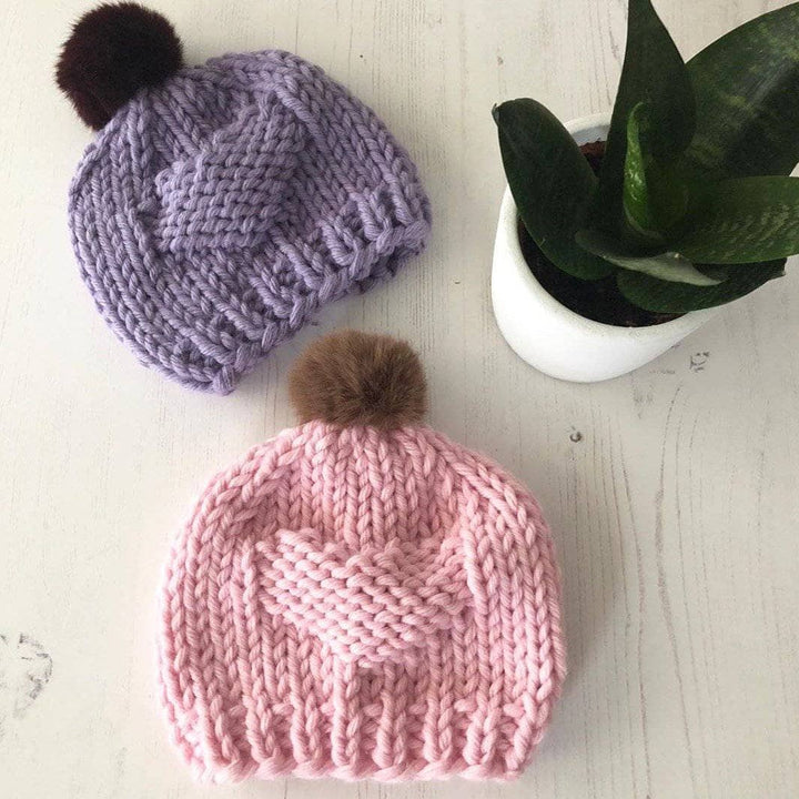 pink and purple hat with pom poms and succulent
