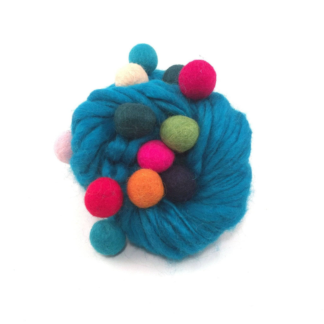 Ball of turquoise felt ball yarn in front of a white background.