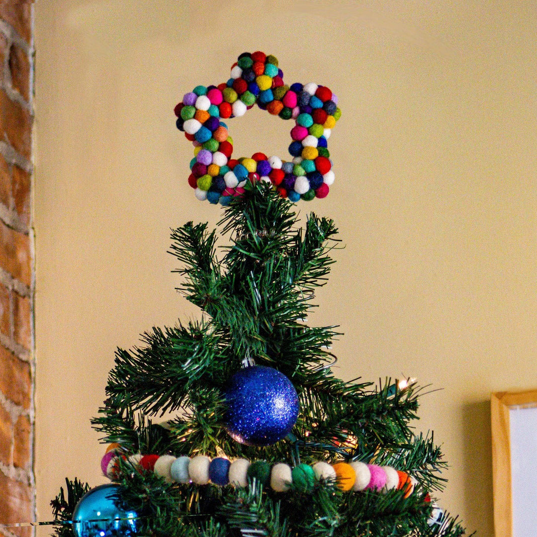 A felt ball star shaped tree topper. The topper is made from rainbow colored felt balls.
