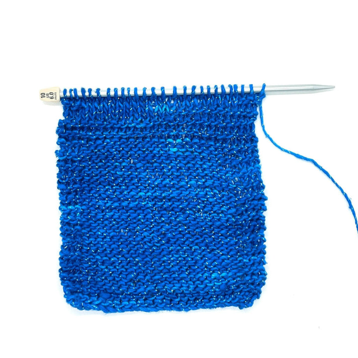 Knit swatch of Silk roving worsted weight classic blue in light blue needle in front of a white background.