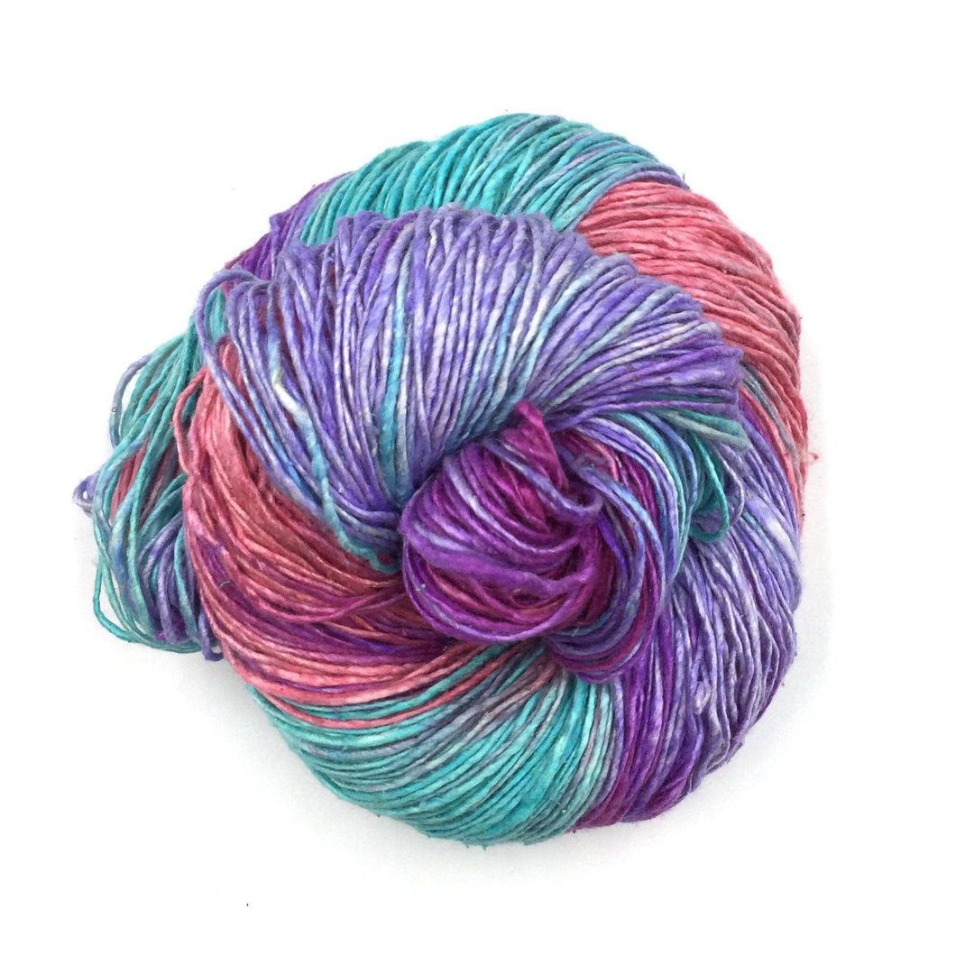 skein of sport weight silk yarn popcicle (purple pink, and teal) in front of a white background.