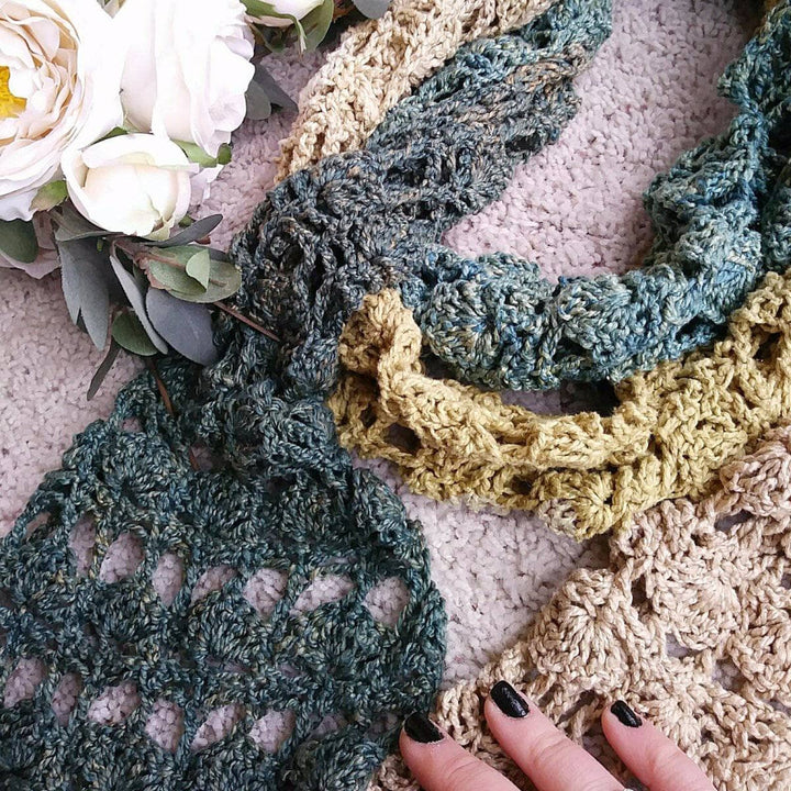 close up of green and beige crochet scarf and a hand