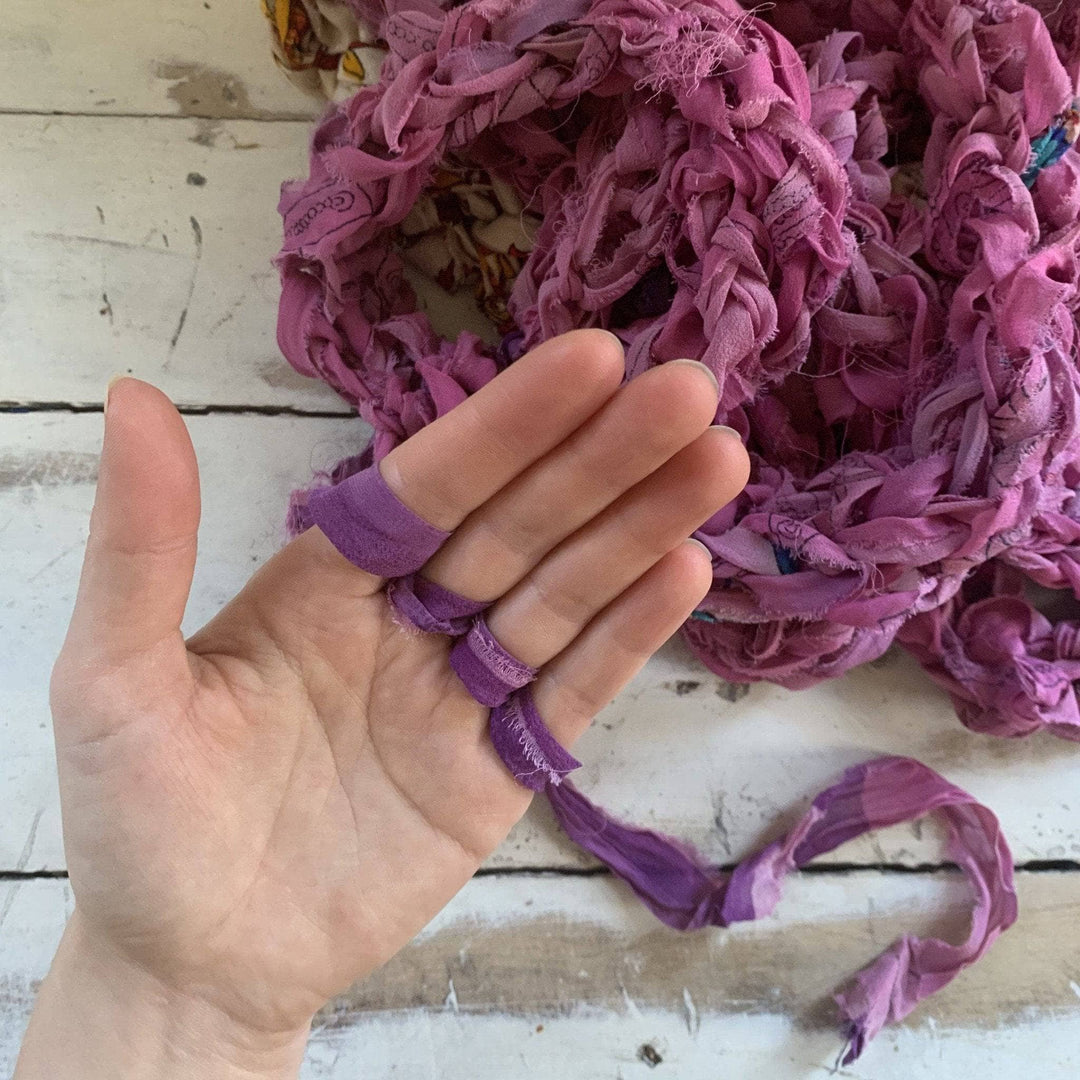 in progress photo of finger knit infinity scarf in front of distressed wood background.