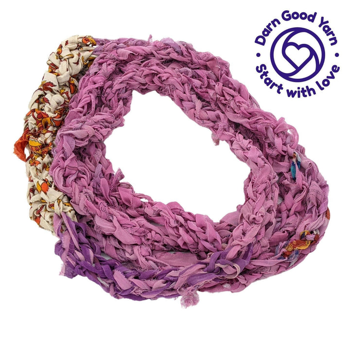 Finger Knit infinity scarf in pink, purple, beige, and orange in front of a white background