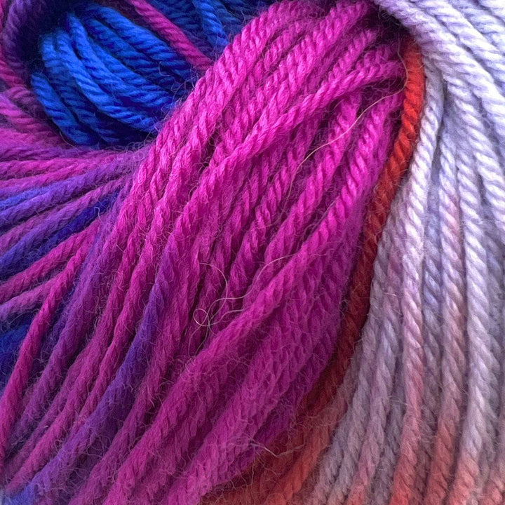Fingering Weight Superwash Merino and Cashmere Blended yarn on a white background with dark blue, purple, pink, red, and light purple strands of yarn.