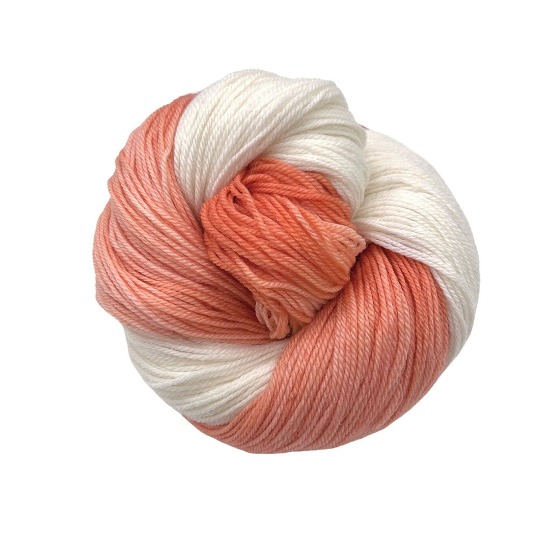 Light orange and white yarn on a white background. Fingering Weight Superwash Merino Wool Blended Yarn.