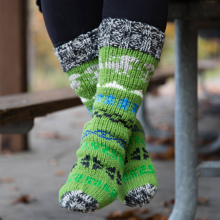 Model's feet dangling while wearing green fleece lined wool socks.  