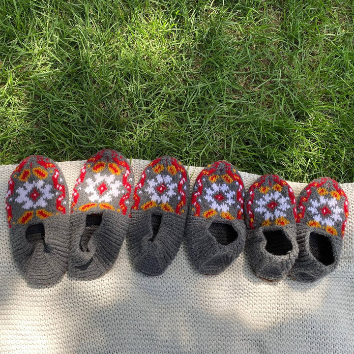 All sizes of the new handmade folklore slippers in a row on a blanket in the grass. 