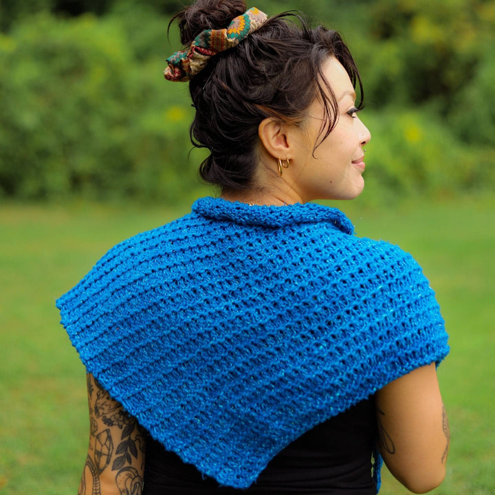 Model has their back to the camera wearing a blue French hen shawl. 