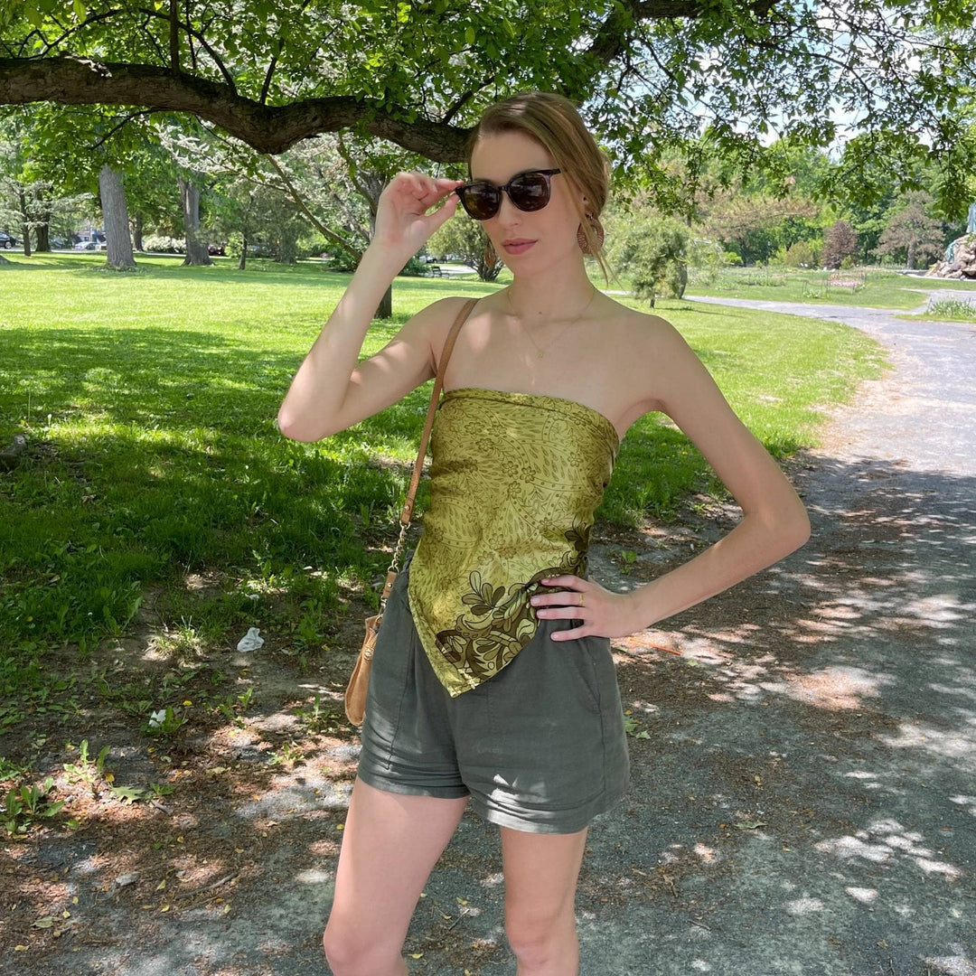 Model is standing in a park wearing a green furoshiki as a top. 