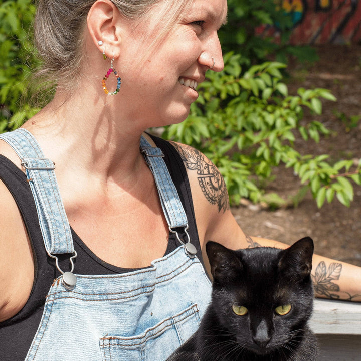 girl wearing Geometric Rainbow Earrings in overalls with black cat