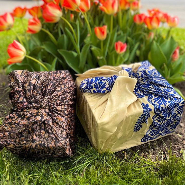Two boxes wrapped in sari silk gift wrap sitting in front of some tulips 