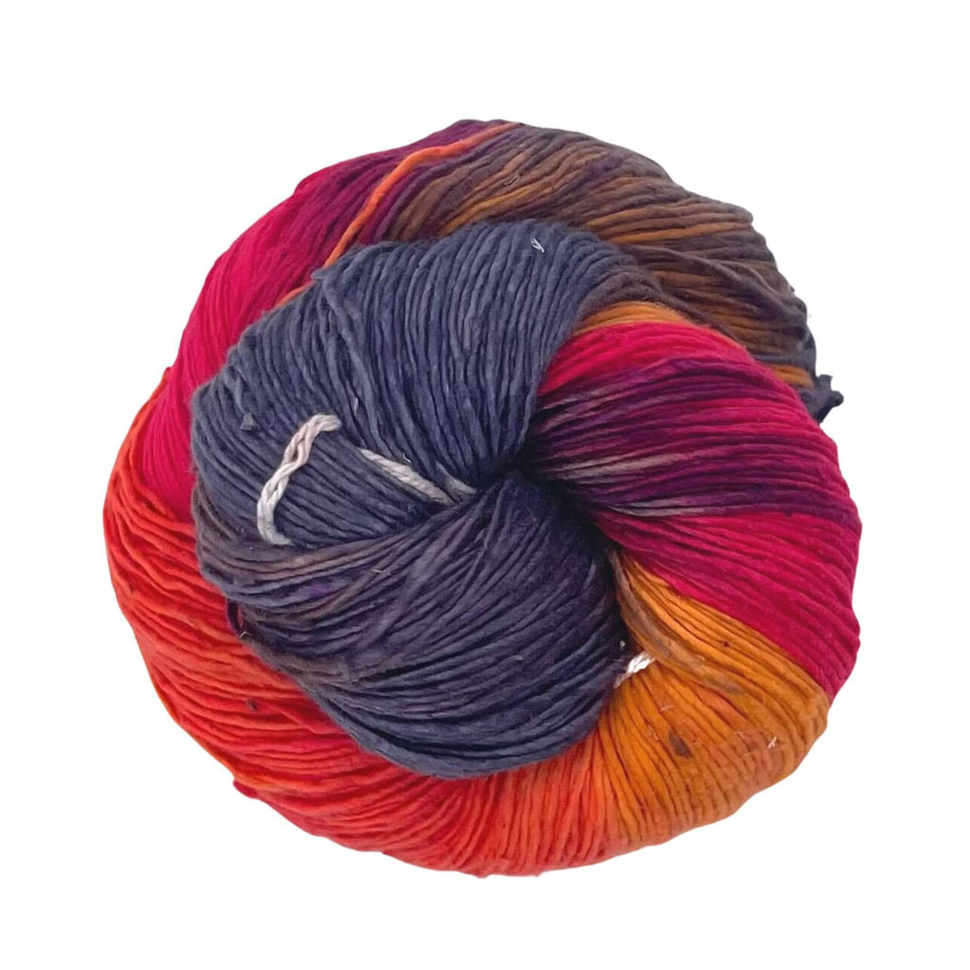A skein of lace weight silk yarn on a white background. Yarn colors are grey, red, pink, orange and yellow.