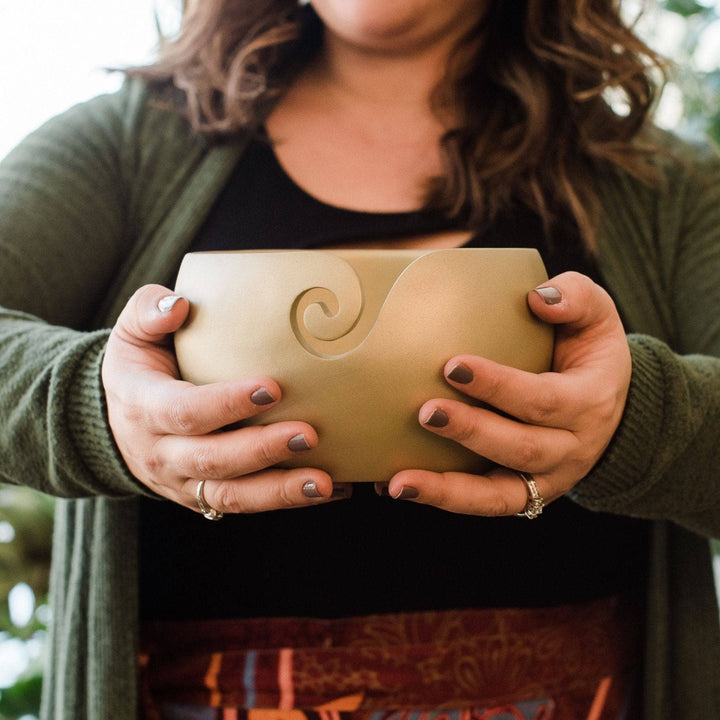 Model holding gold wooden yarn bowl outstretched .