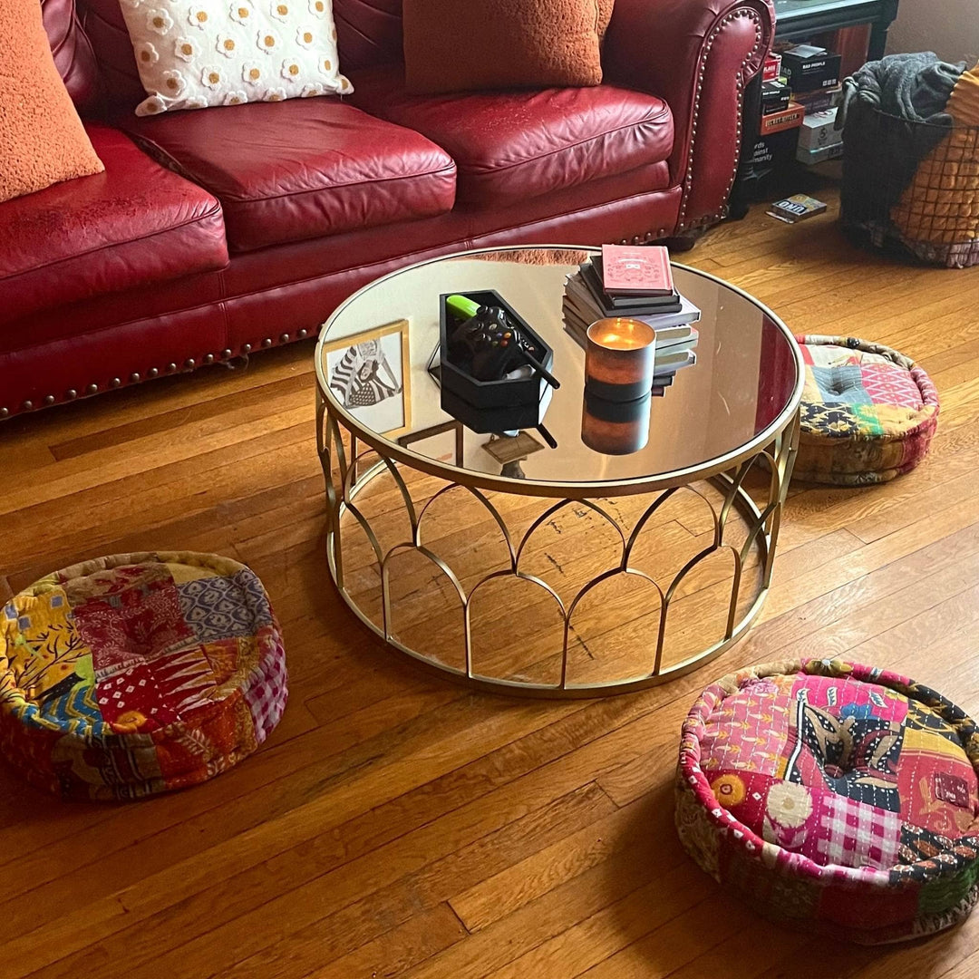Three One of a Kind Hand Embroidered Pouf around a coffee table on a wooden floor. 