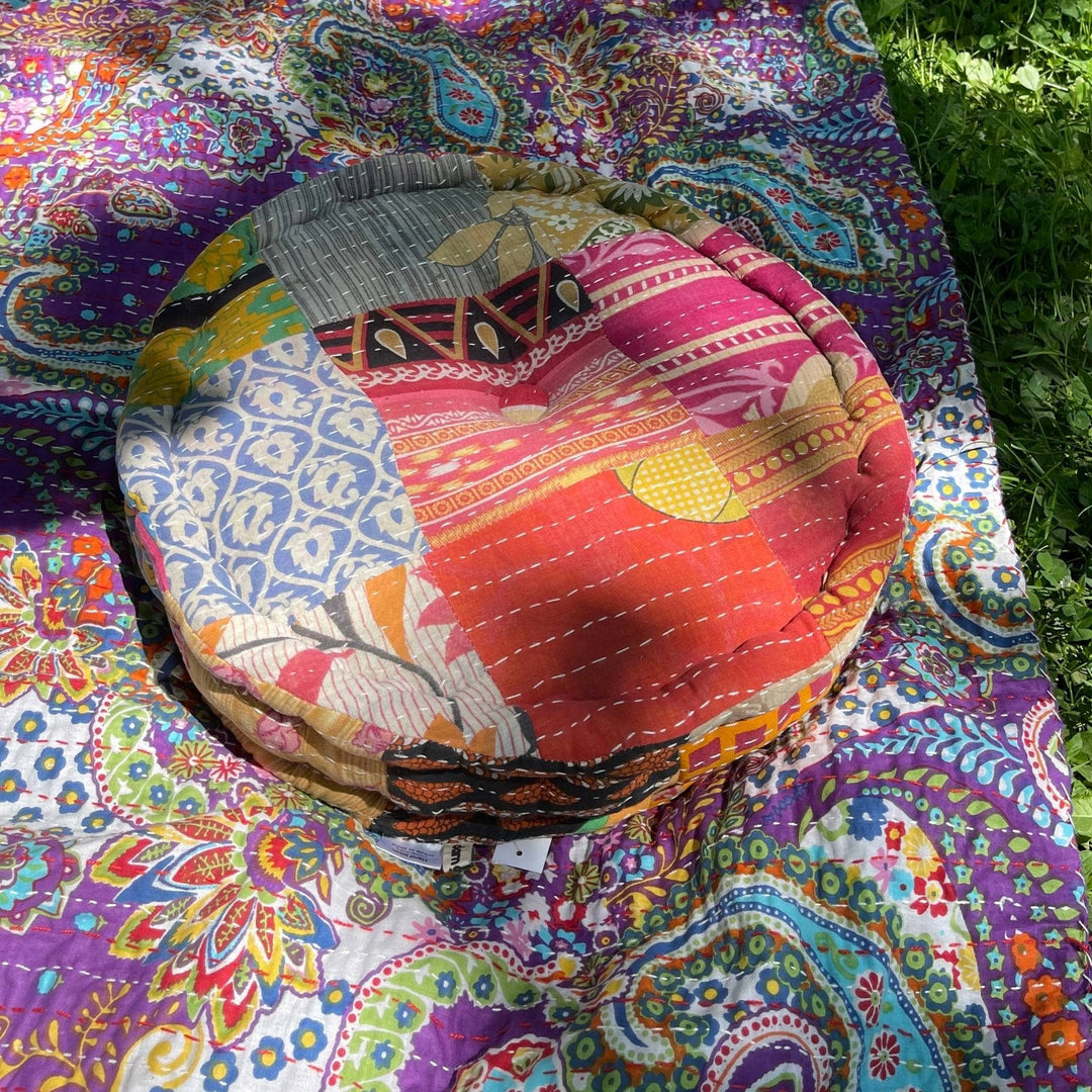 One of a Kind Hand Embroidered Pouf outside on a picnic blanket. 