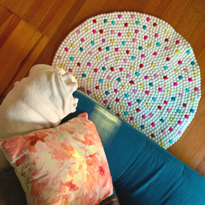 A vibrant multi-color ball rug under a teal couch