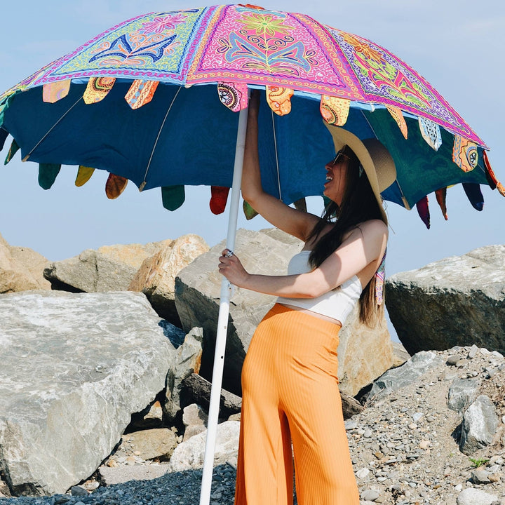 Model is on the beach standing under the one of a kind handmade beach umbrella. 