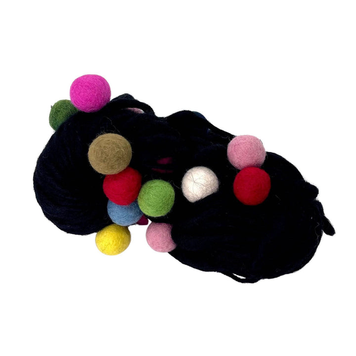 A hank of black felt ball yarn on a white background. The felt balls on this yarn are rainbow in color.