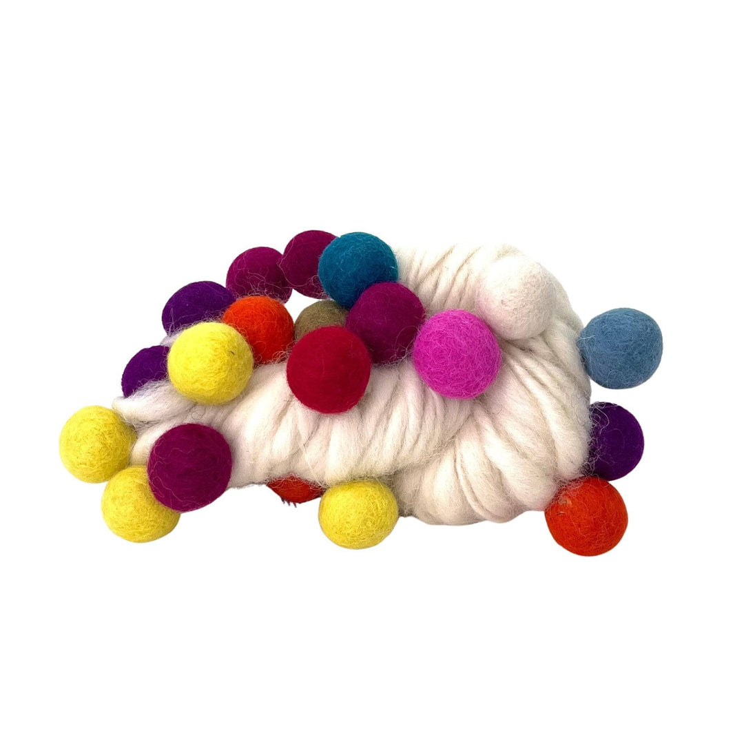 A hank of white felt ball yarn on a white background. The felt balls are vibrant and in rainbow colors.