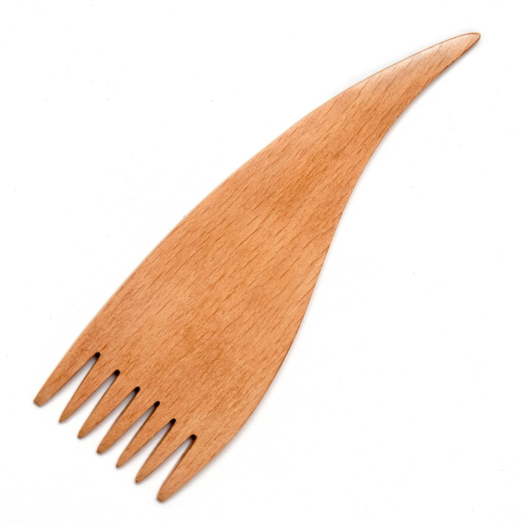 Wooden weaving comb in front of a white background. Comb is a curvy teardrop shape with 7 tines.