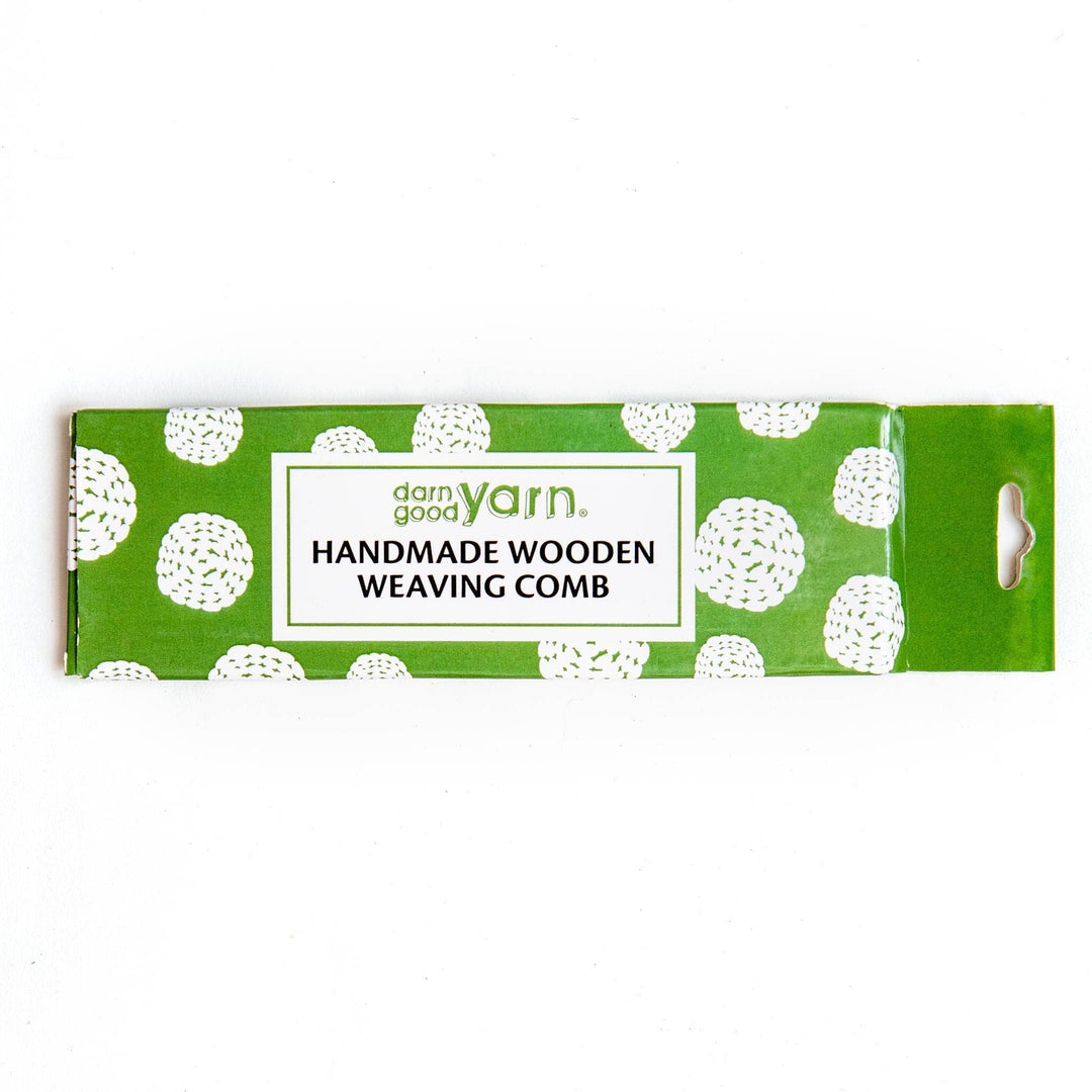 Green and white cardboard box in front of a white background. Text reads darn good yarn handmade wooden weaving comb. 