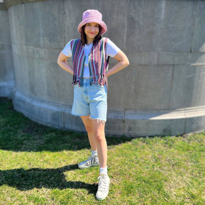 Model standing outside in front of a cement wall wearing the lavender heather bolero vest.  