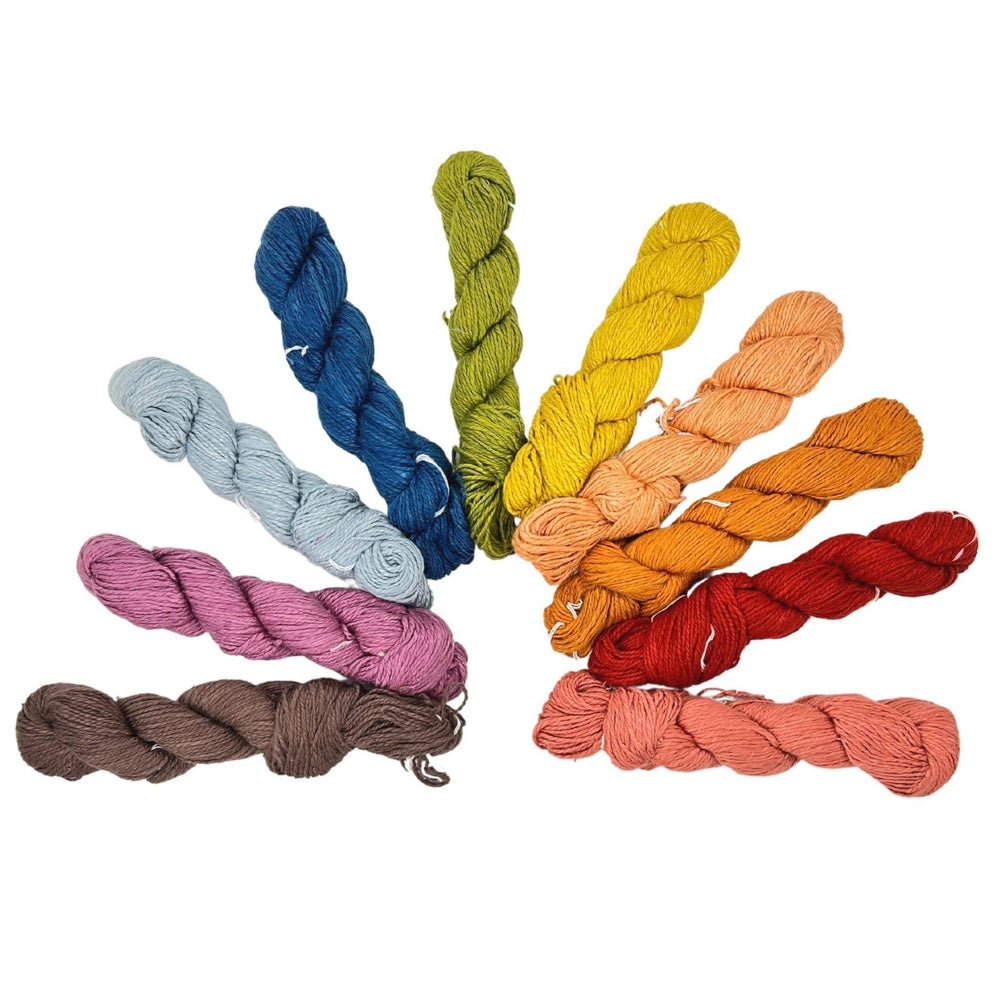 10 mini skeins in an array of colors arranged in a rainbow shape in front of a white background.