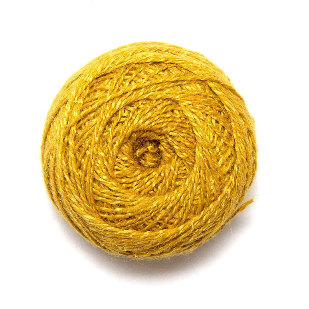 cake of herbal dyed silky wool yarn in colorway marigold. 1 ply lighter yellow and one ply darker yellow create a marled effect throughout, colors are similar in value creating a heathered effect visually.