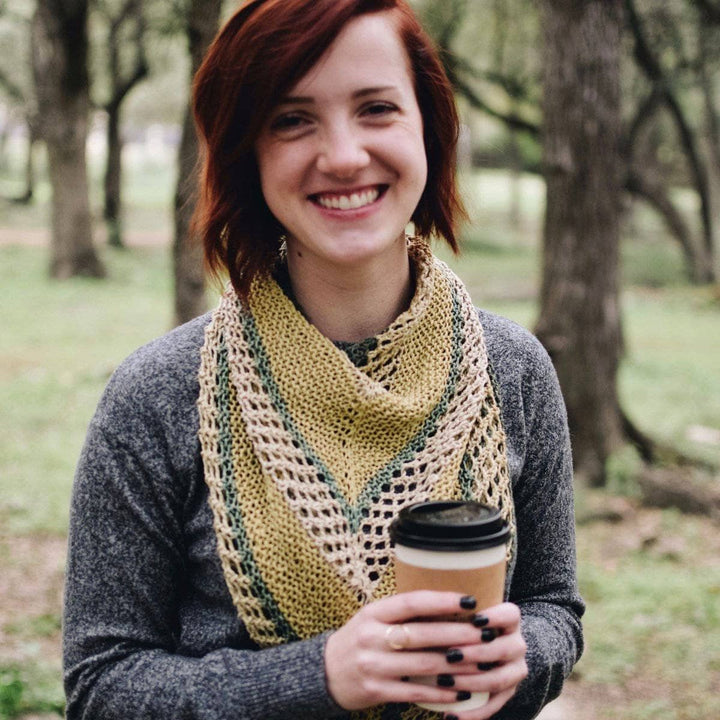 woman wearing the Hibiscus Shawl while smiling and holding a coffee up