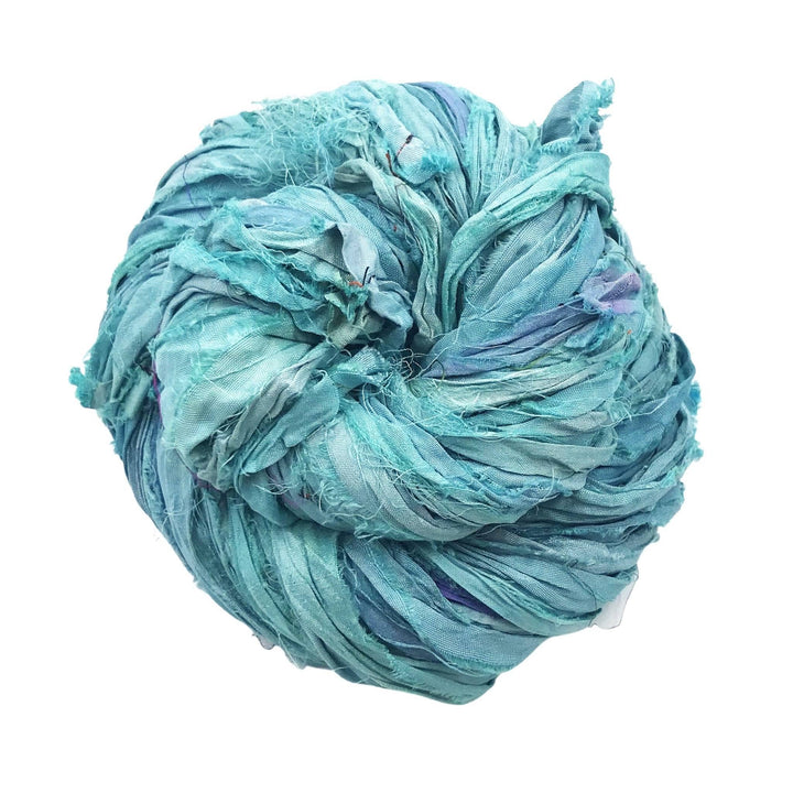 Single skein of sari silk ribbon yarn (light blue) in front of a white background