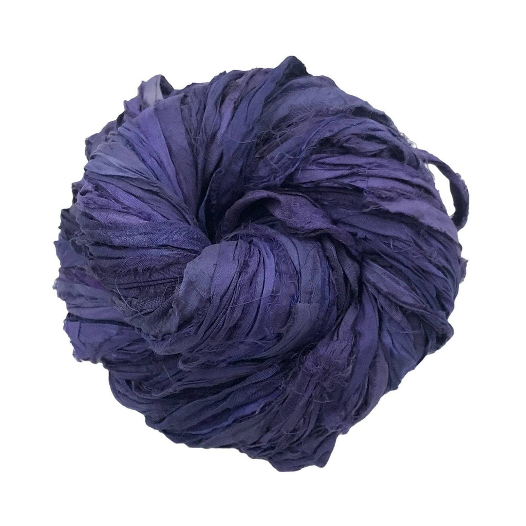 Single skein of sari silk ribbon yarn (deep purple) in front of a white background