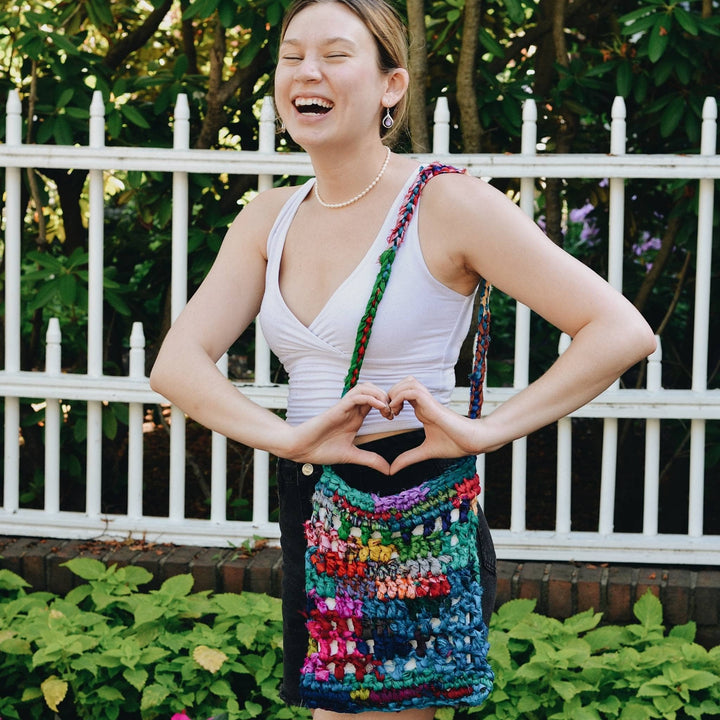 Model wearing hidden heart crochet bag made from multicolor recycled silk ribbon yarn