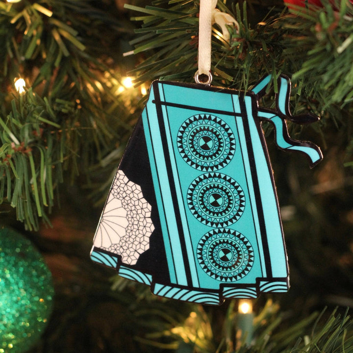 A blue skirt christmas tree ornament hanging on a christmas tree.