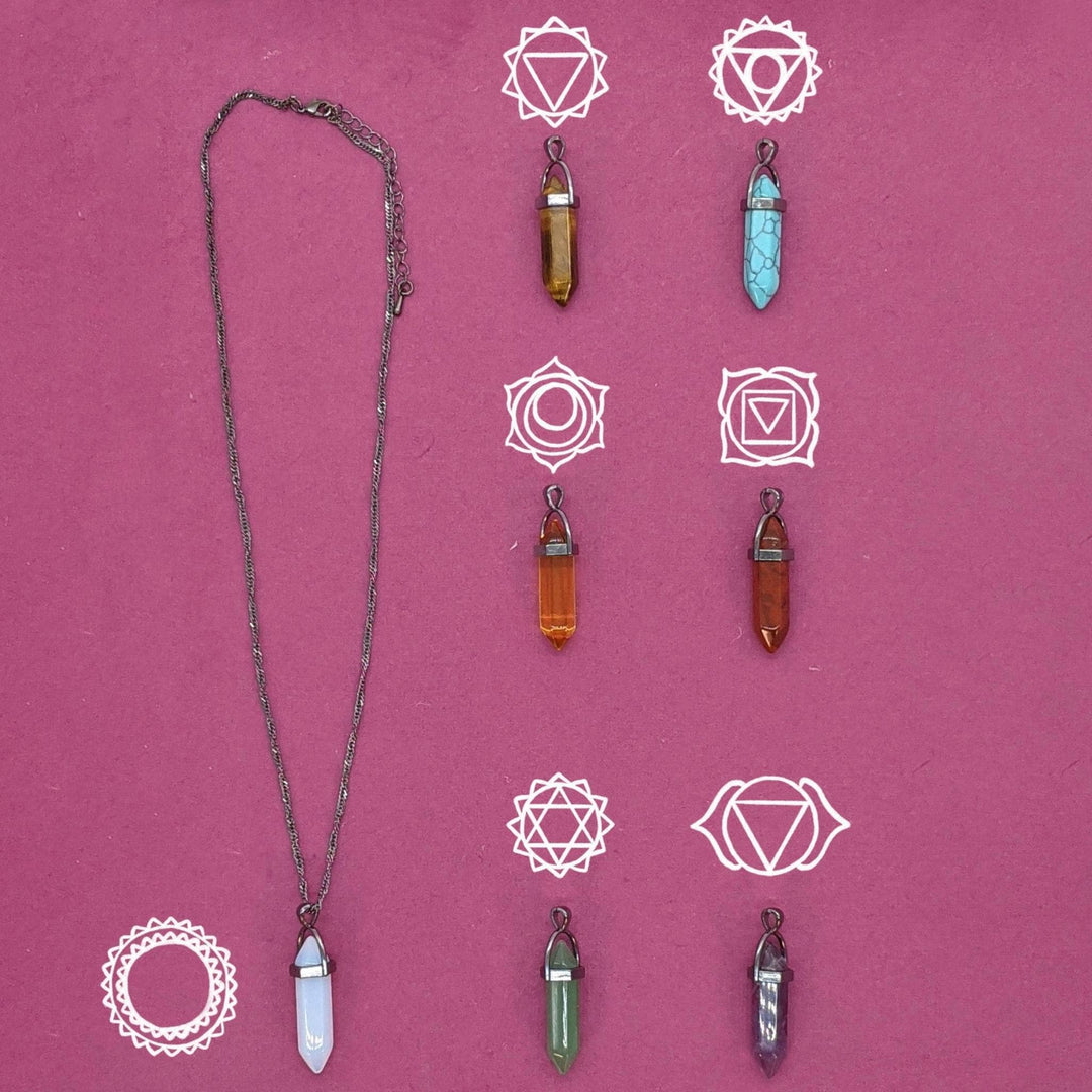 Interchangeable Chakra Necklace on pink background with charka symbols above each stone. 