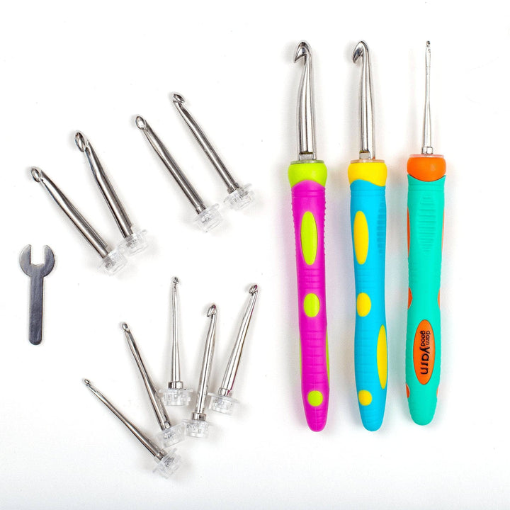 interchangeable crochet hook set outside of case, in front of a white background. Left to right, wrench tool for changing attachments, 9 loose crochet hook attachments, 3 ergonomic crochet hook handles with hooks attached. 