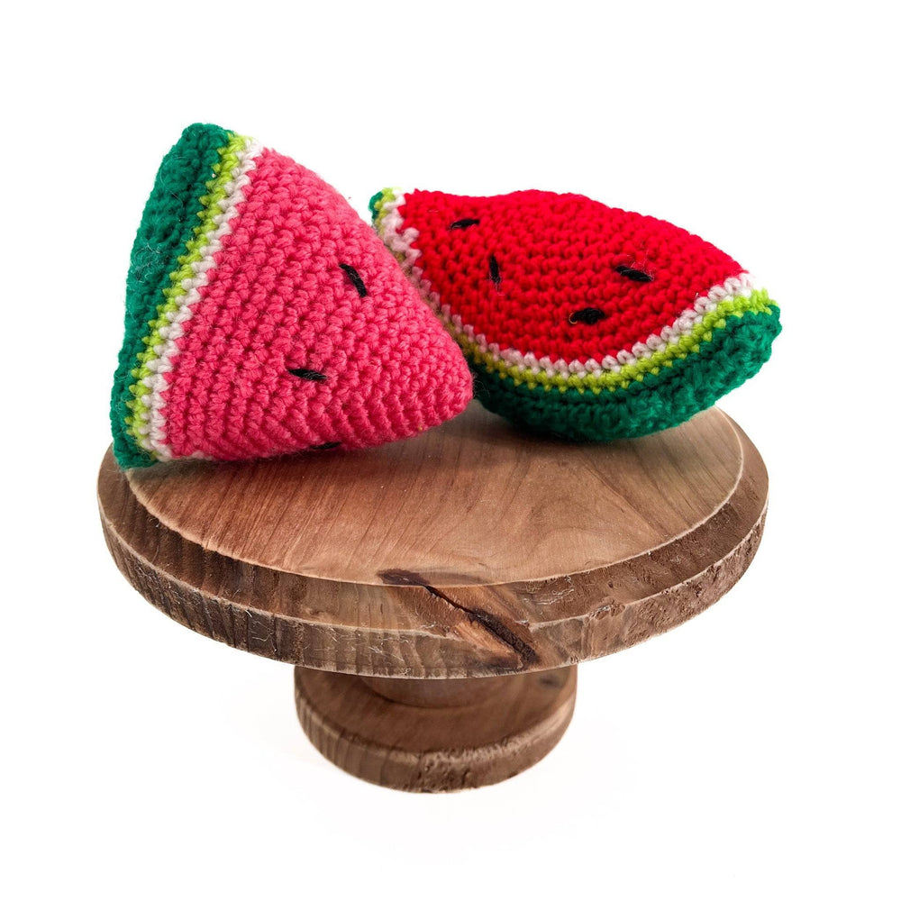 Image of watermelon amigurumi sitting on a wooden pedestal with a white background   