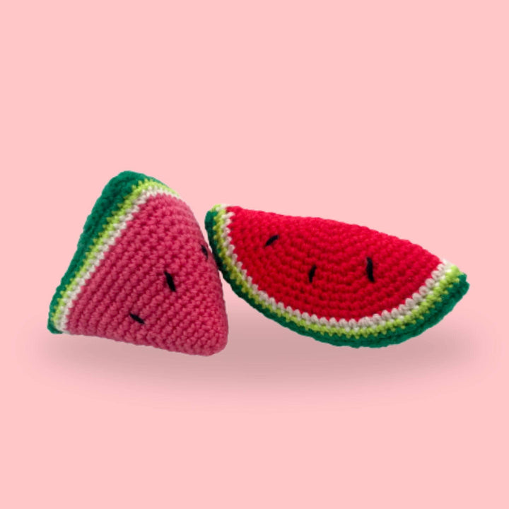 Two Knit Watermelon Slices sitting on a plain background.