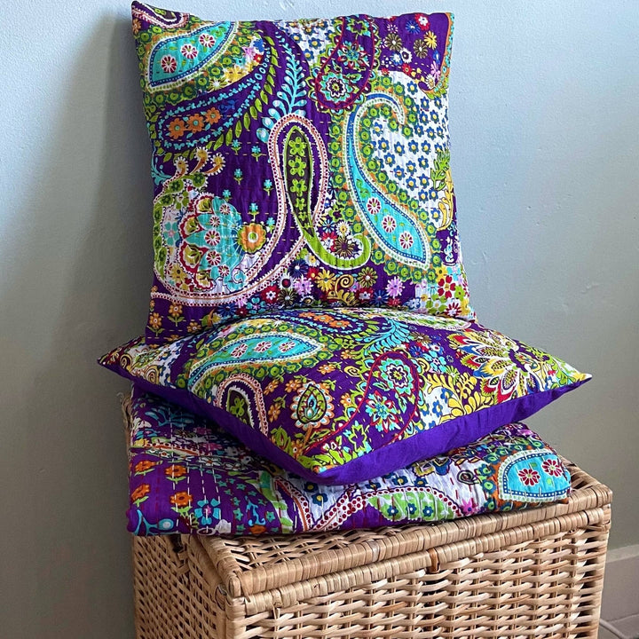 Paisley Fiesta pillows stacked up on a paisley fiesta kantha quilt on a wicker hamper. 