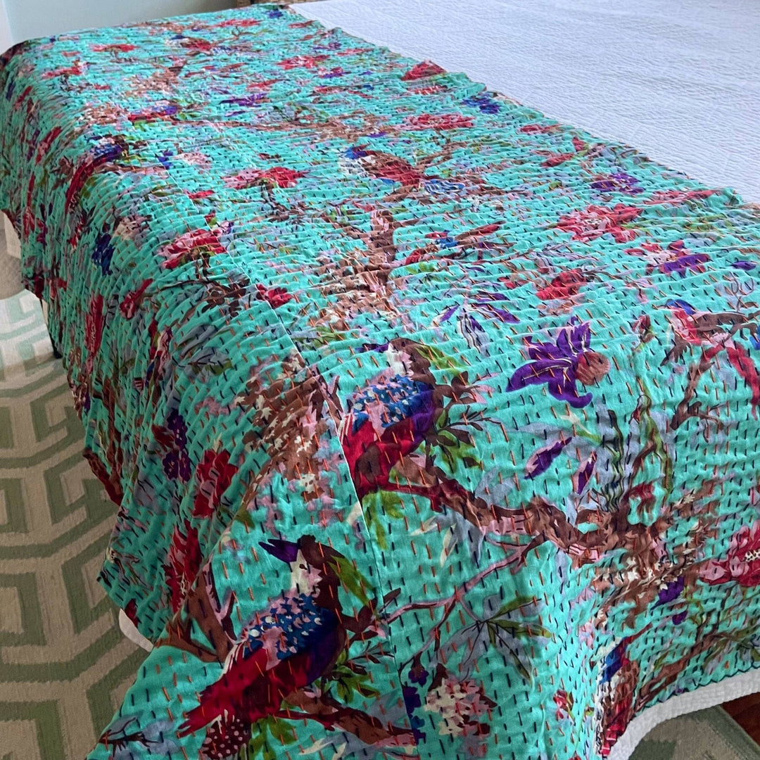 Closeup of robin's egg Kantha Quilt at the bottom of a bed. 