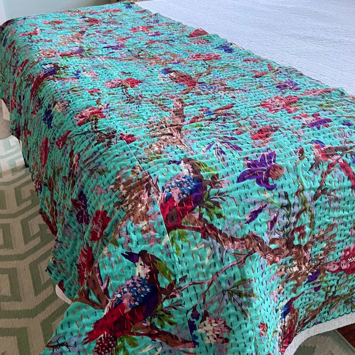 Closeup of robin's egg Kantha Quilt at the bottom of a bed. 