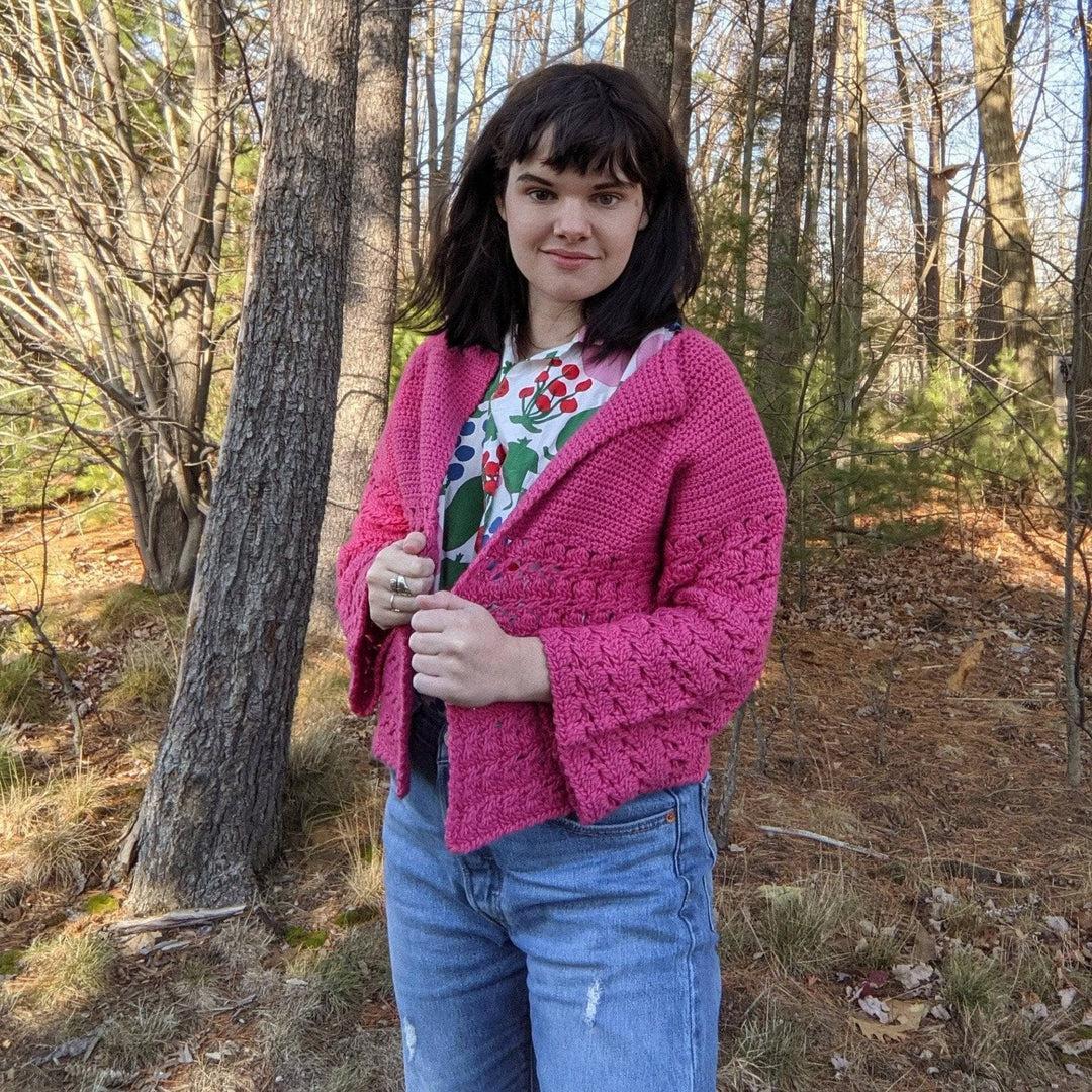 a person wearing a pink cardigan outside