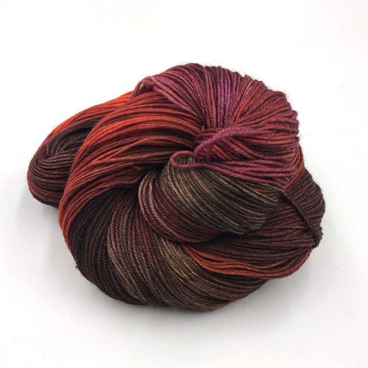 Superwash merino wool sock yarn ball in Bravery (red) on a white background