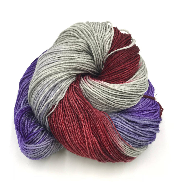Superwash merino wool sock yarn ball in Romantico (gray, red, purple) on a white background