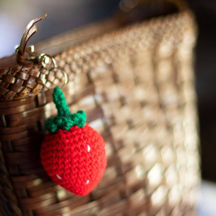 Crochet amigurumi strawberry keychain attached to basketweave purse