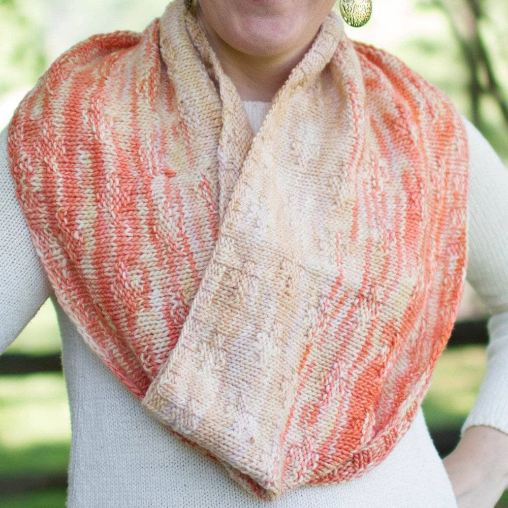 A woman wearing a pink and beige infinity scarf outside